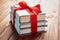 Stack of three books tied with a red ribbon with a bow on a wooden background: concept of a good book - a good gift