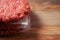 Stack of three fresh uncooked beef burgers separated with cooking paper on a cutting wooden board and table. Food industry., Close