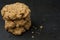 Stack of three oatmeal cookies with crumbs on black counter