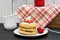 A stack of three pancakes garnished with fresh strawberry slices and whipped cream
