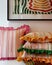 A stack of three striped pillows with curled edges, displayed on a shelf