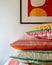 A stack of three striped pillows with curled edges, displayed on a shelf