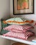 A stack of three striped pillows with curled edges, displayed on a shelf