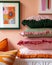 A stack of three striped pillows with ruffled edges, displayed on a shelf next to a framed work of art