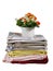 A stack of towels of different colors and a bouquet of flowers in a vase isolated on a white background