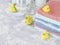 Stack of towels with yellow rubber bath ducks on white marble background, space for text, selective focus