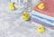 Stack of towels with yellow rubber bath ducks on white marble background, space for text, selective focus