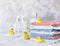 Stack of towels with yellow rubber bath ducks on white marble background, space for text, selective focus