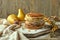 A stack of traditional pancakes on board, two pears in the backdrop, powdered sugar, a sprig of sea buckthorn, and a spoon for