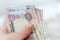 Stack of UAE dirhams in woman`s hands on blurred background.