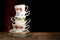 Stack of various English vintage porcelain teacups with floral decoration on dark background