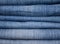 stack of various shades of blue jeans as background