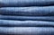 stack of various shades of blue jeans as background
