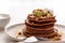 Stack of vegetarian chocolate pancakes with hazelnuts, kiwi, honey on plate