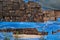 Stack of weathered wooden railroad cross ties covered by blue torn plastic
