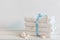 A stack of white bath towels with blue tape and different seashells on white wooden table. Spa and wellness, cotton