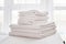 Stack of white clean bath towels on bed sheet in modern bedroom interior, copy space.