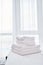 Stack of white terry bath towels on bed sheet in modern hotel bedroom interior, copy space