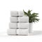 A stack of white towels sitting next to a potted plant.