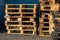 A stack of wooden pallets in an internal warehouse. An outdoor pallet storage area under the roof next to the store. Piles of Euro