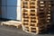 A stack of wooden pallets in an internal warehouse. An outdoor pallet storage area under the roof next to the store. Piles of Euro