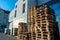 A stack of wooden pallets in an internal warehouse. An outdoor pallet storage area under the roof next to the store. Piles of Euro