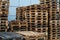 A stack of wooden pallets in an internal warehouse. An outdoor pallet storage area under the roof next to the store. Piles of Euro