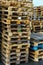 A stack of wooden pallets in an internal warehouse. An outdoor pallet storage area under the roof next to the store. Piles of Euro