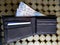 stacked coins of ten mexican pesos and black leather wallet with banknotes of 500 pesos