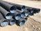 Stacked corrugated pvc-pipes at the outdoor warehouse. Drainage, plumbing, stormwater equipment