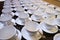 Stacked empty teacups with teaspoons at a function over white ba