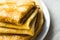 Stacked folded crepes on white plate on linen cloth background, closeup, breakfast