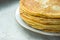 Stacked golden crepes on white plate on linen cloth background, closeup, breakfast