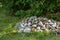 Stacked large stones or rocks on a field of green grass. Rocks along a remote hiking trail in nature. Collected pile of