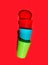 Stacked multicolored plastic drinking cups on solid red background. Environmental protection plastic-free alternatives