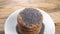 Stacked oatmeal cookies in a white plate on a rustic wooden background sprinkle dry poppy seeds in slow motion.