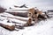 Stacked sawed pine logs in a pile under snow in overcast winter day