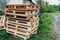 Stacked wooden pallets are stacked on the streets outside the premises. Old pallets at the building on the road