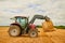 Stacking bales of hay. a farmer stacking hale bales with a tractor on his farm.