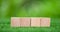 Stacking blank wooden cubes on green background with copy space for input wording and infographic icon. Empty brown wooden object