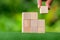 Stacking blank wooden cubes on green background with copy space for input wording and infographic icon. Empty brown wooden object