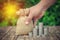 Stacking coins with hand picking holding money bag sack on the wooden table.