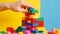 Stacking colorful plastic blocks by hand on a yellow background