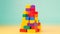 Stacking colorful plastic blocks by hand on a yellow background