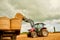 Stacking those hay bales. Shot of a farmer stacking hale bales with a tractor on his farm.