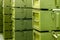 Stacks of abstract green military crates without any markings - close-up with selective focus and background blur