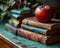 Stacks of books set on a green canvas accented by a red apple, educational photo