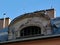 Stacks and brick chimneys and arched old dormer on sloped metal roof