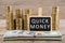 Stacks of coins and dollar bills, blackboard with text QUICK MONEY