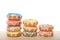 Stacks of colorful frosted candy coated donuts on a light wood table isolated